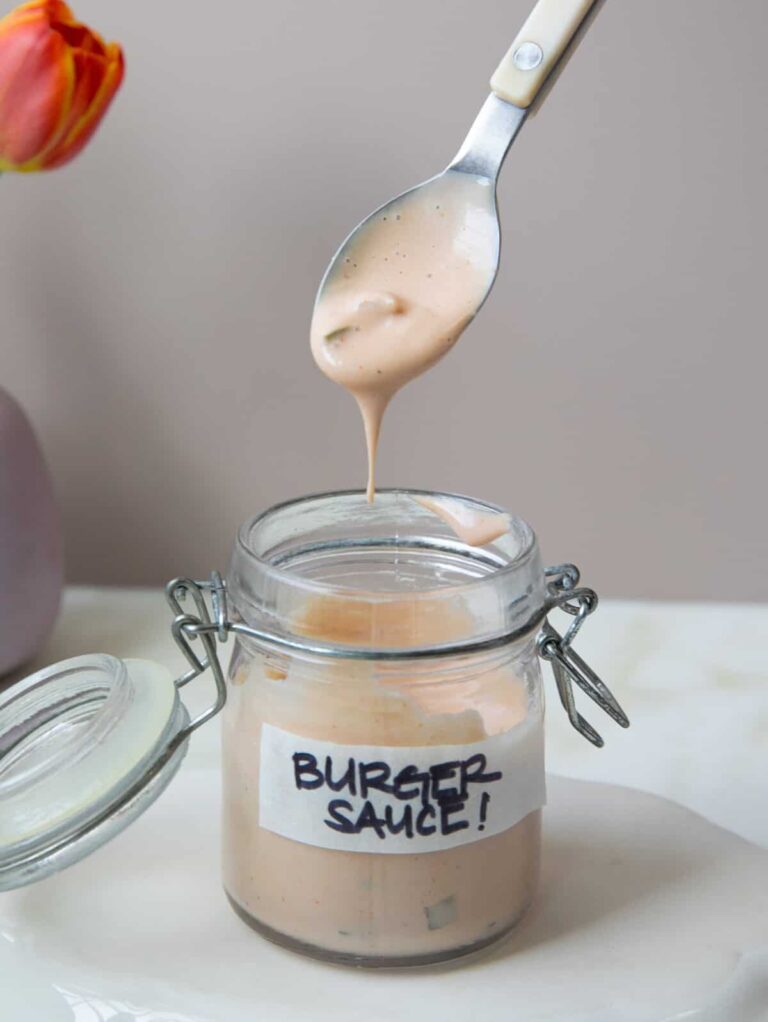 एक चम्मच के साथ एक जार में बर्गर सॉस अंदर डूबा हुआ।