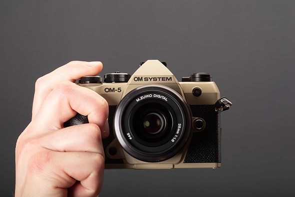 a_hand_holds_the_om-5_ii_in_front_of_dark_background.jpeg