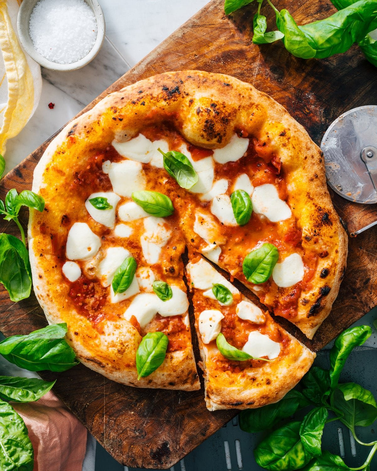 पिज्जा सॉस और पिज्जा कटर के साथ मार्गेरिटा पिज्जा।