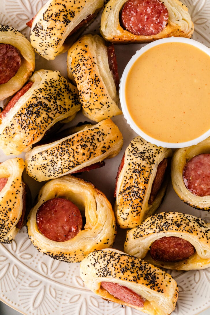 पफ पेस्ट्री और स्मोक्ड सॉसेज से बने कंबल में बड़े सूअर, सुनहरा होने तक पकाया जाता है और सरसों की चटनी के साथ परोसा जाता है।