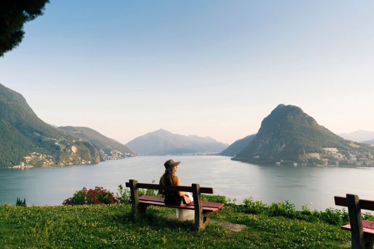 Woman-relaxes-on-bench-looking-over-lake-and-mountains-in-Switzerland_AscentXmedia.jpg
