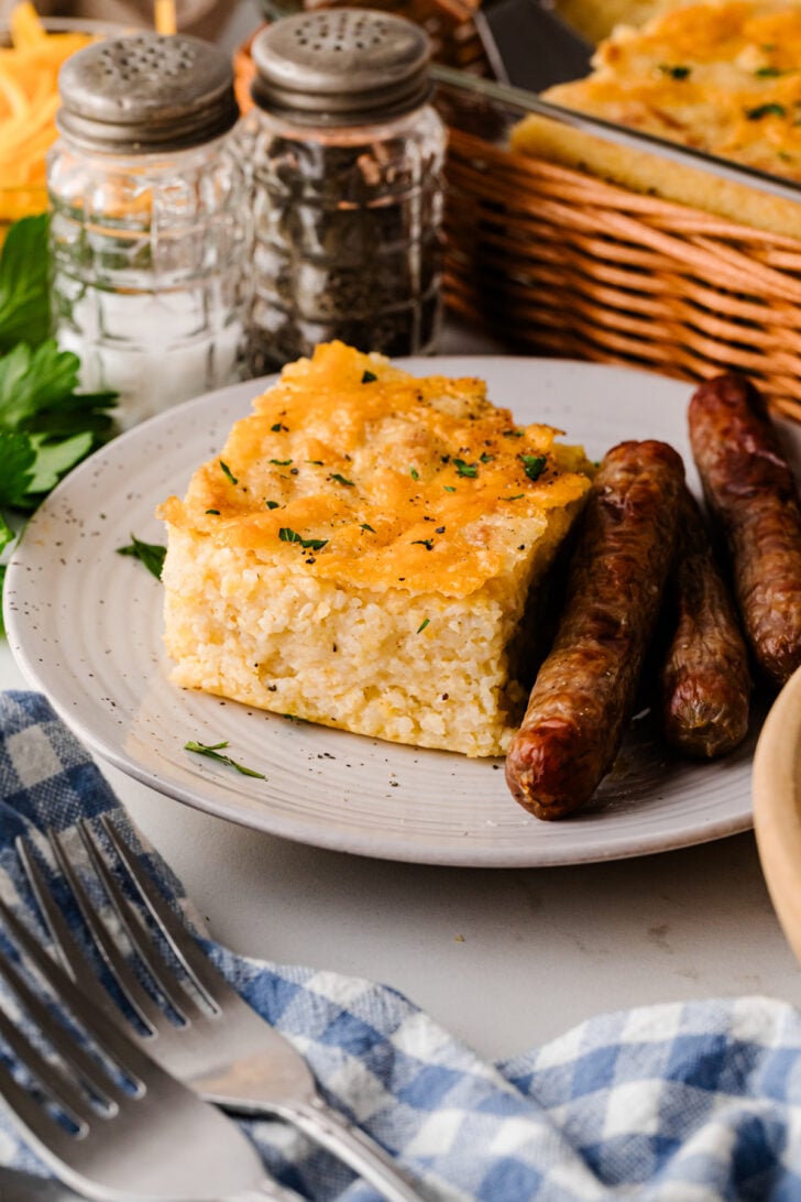 सुनहरे, बुलबुलेदार शीर्ष के साथ एक सफेद डिश में बेक्ड पनीर ग्रिट्स पुलाव - छुट्टियों और ब्रंच के लिए एक क्लासिक दक्षिणी मेक-फॉरवर्ड साइड डिश।