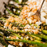 एक सर्विंग प्लेट पर नींबू पैंको और फेटा के साथ भुना हुआ शतावरी, आसान स्प्रिंग साइड डिश।