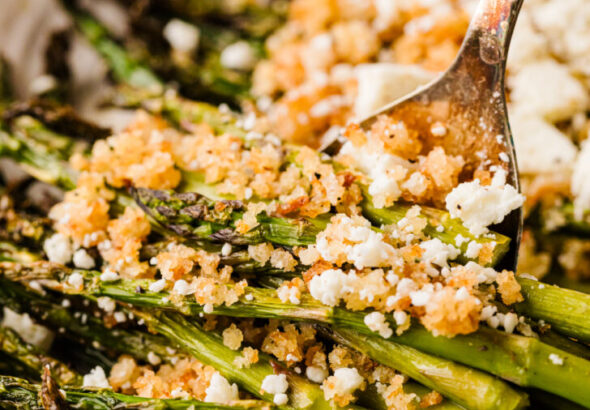 एक सर्विंग प्लेट पर नींबू पैंको और फेटा के साथ भुना हुआ शतावरी, आसान स्प्रिंग साइड डिश।